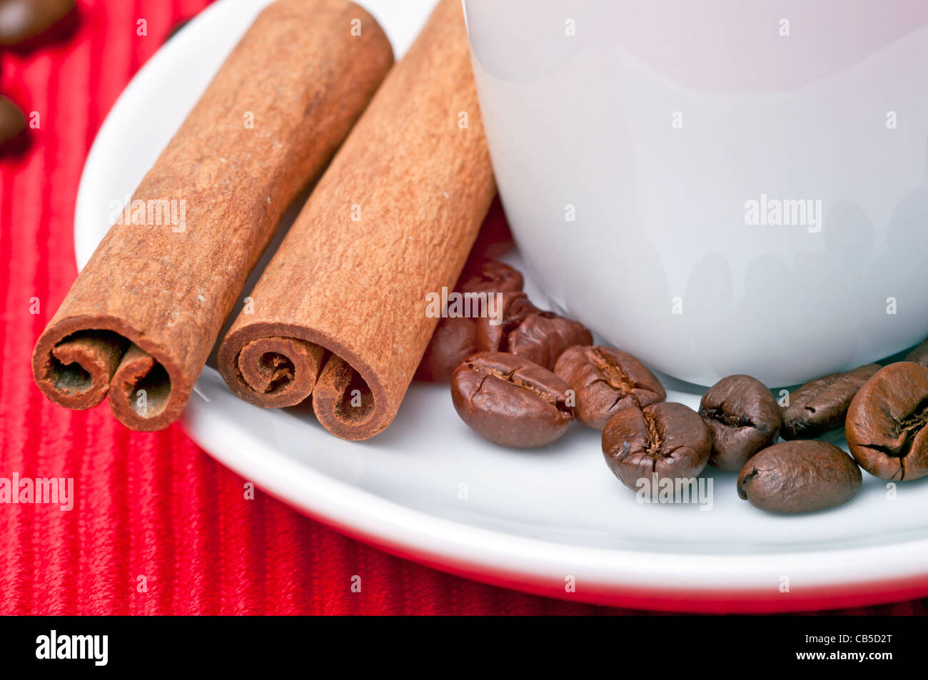 Tazza da caffè con cannella, granelli di caffè e un cucchiaio dal lato. Foto Stock
