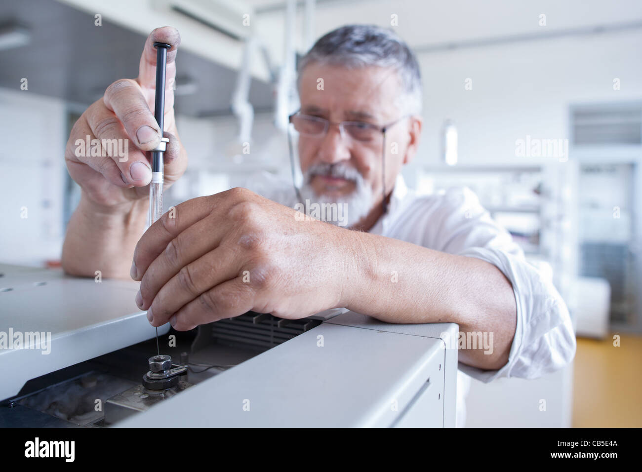 Maschio senior researcher di effettuare attività di ricerca scientifica in un laboratorio usando un cromatografo a gas Foto Stock