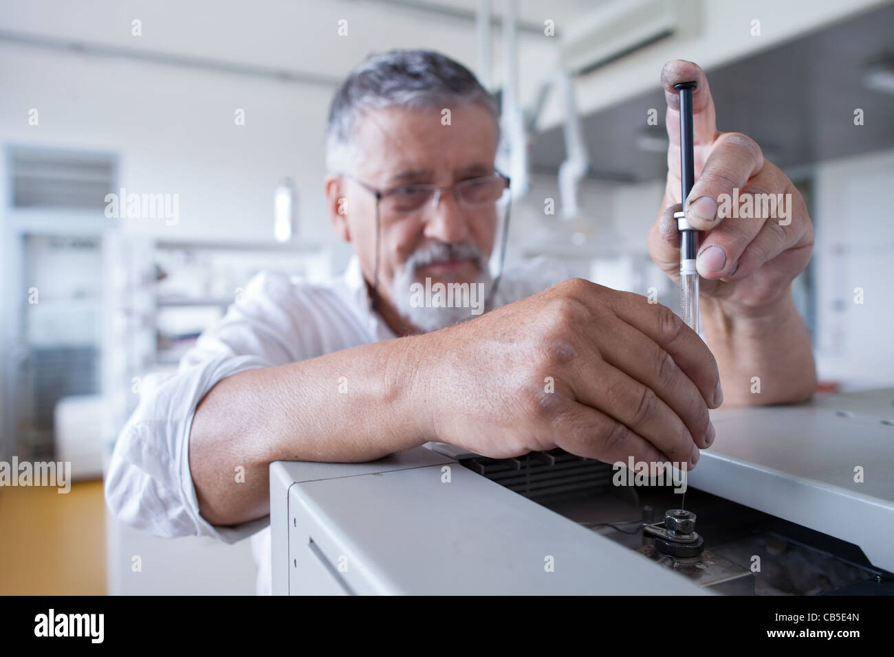 Maschio senior researcher di effettuare attività di ricerca scientifica in un laboratorio usando un cromatografo a gas Foto Stock