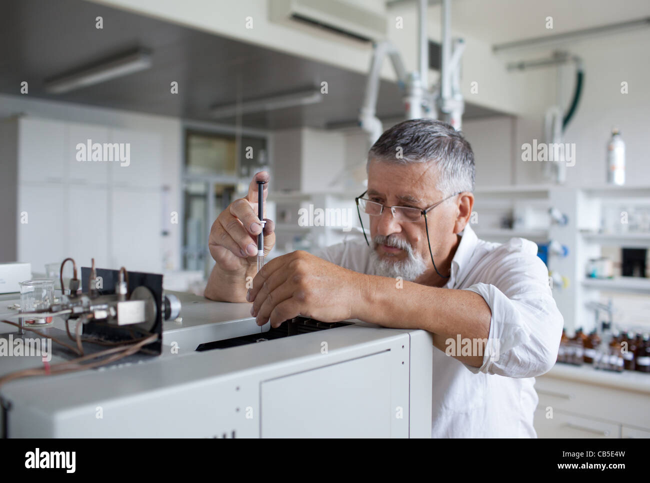 Maschio senior researcher di effettuare attività di ricerca scientifica in un laboratorio usando un cromatografo a gas Foto Stock