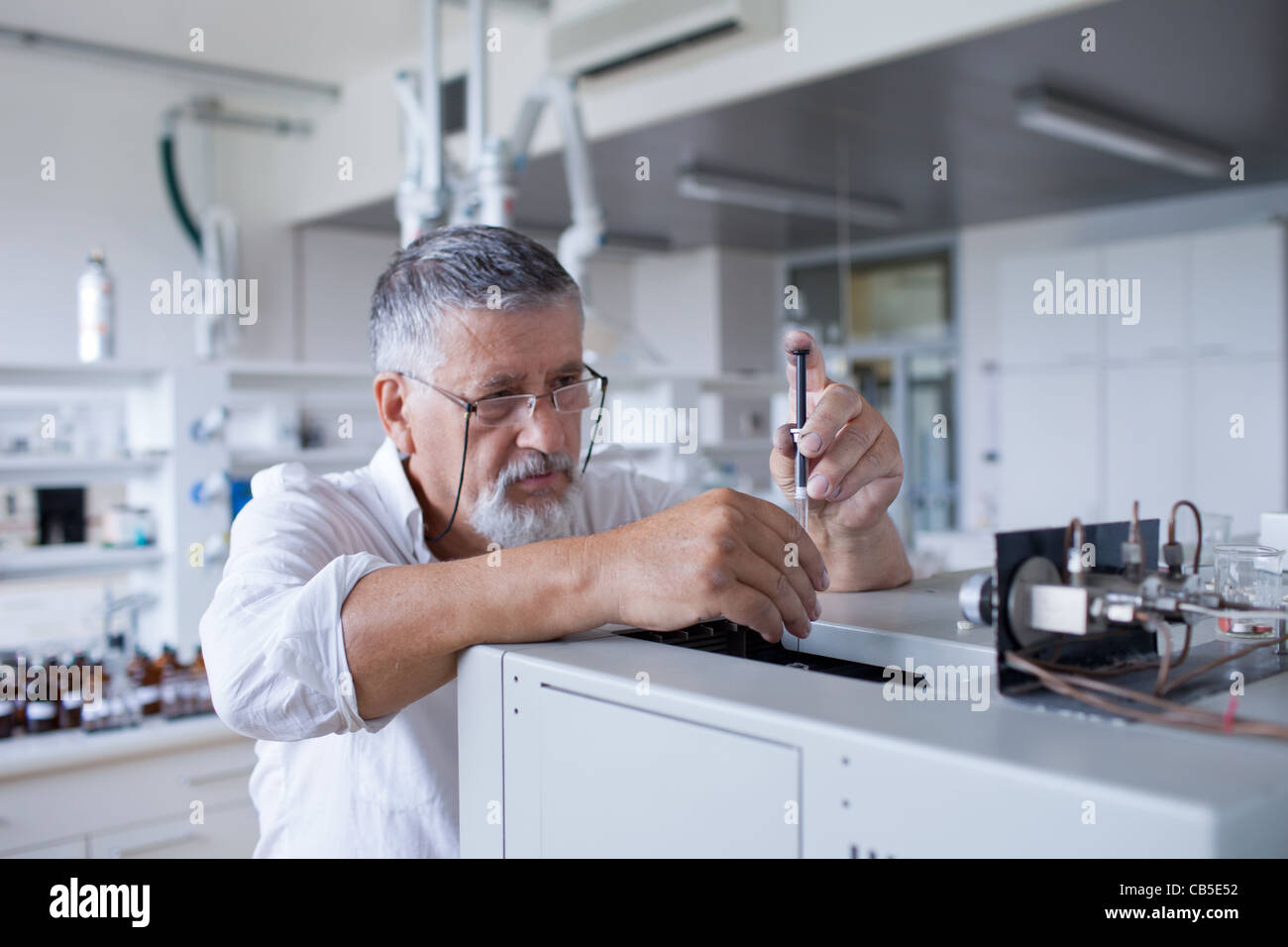 Maschio senior researcher di effettuare attività di ricerca scientifica in un laboratorio usando un cromatografo a gas Foto Stock