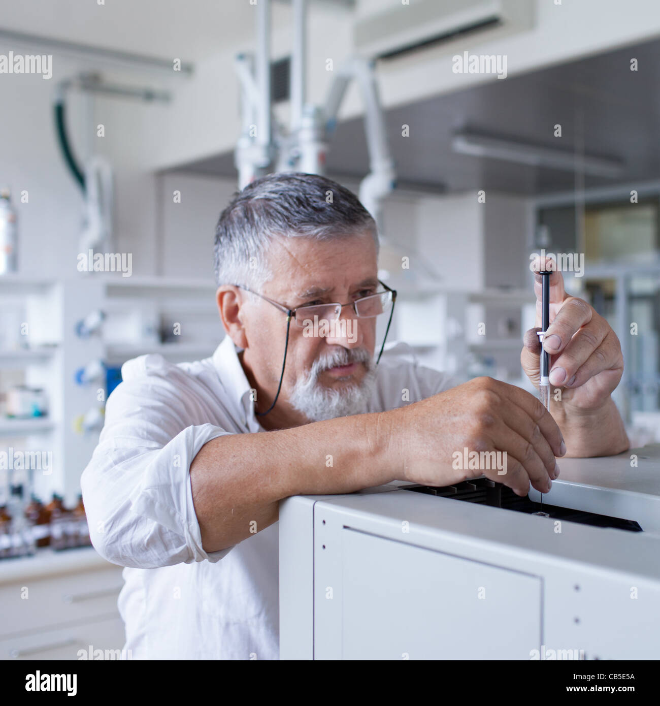 Maschio senior researcher di effettuare attività di ricerca scientifica in un laboratorio usando un cromatografo a gas Foto Stock
