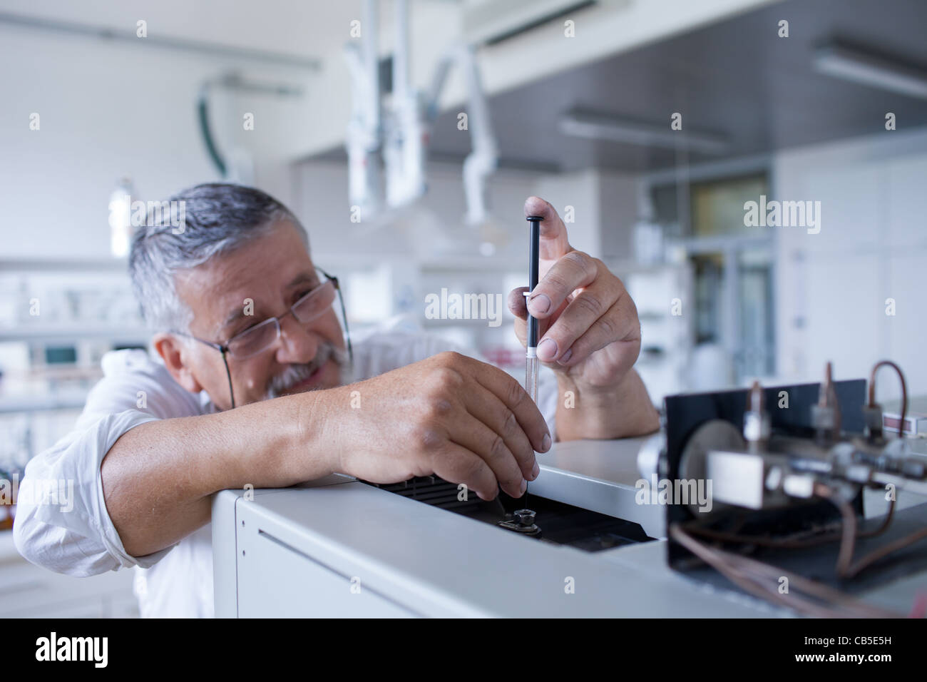 Maschio senior researcher di effettuare attività di ricerca scientifica in un laboratorio usando un cromatografo a gas Foto Stock