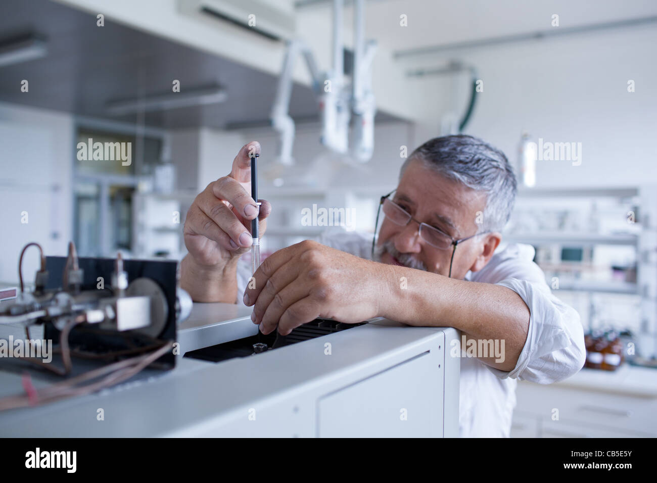 Maschio senior researcher di effettuare attività di ricerca scientifica in un laboratorio usando un cromatografo a gas Foto Stock
