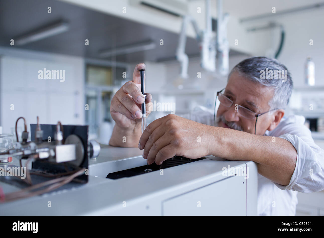 Maschio senior researcher di effettuare attività di ricerca scientifica in un laboratorio usando un cromatografo a gas Foto Stock