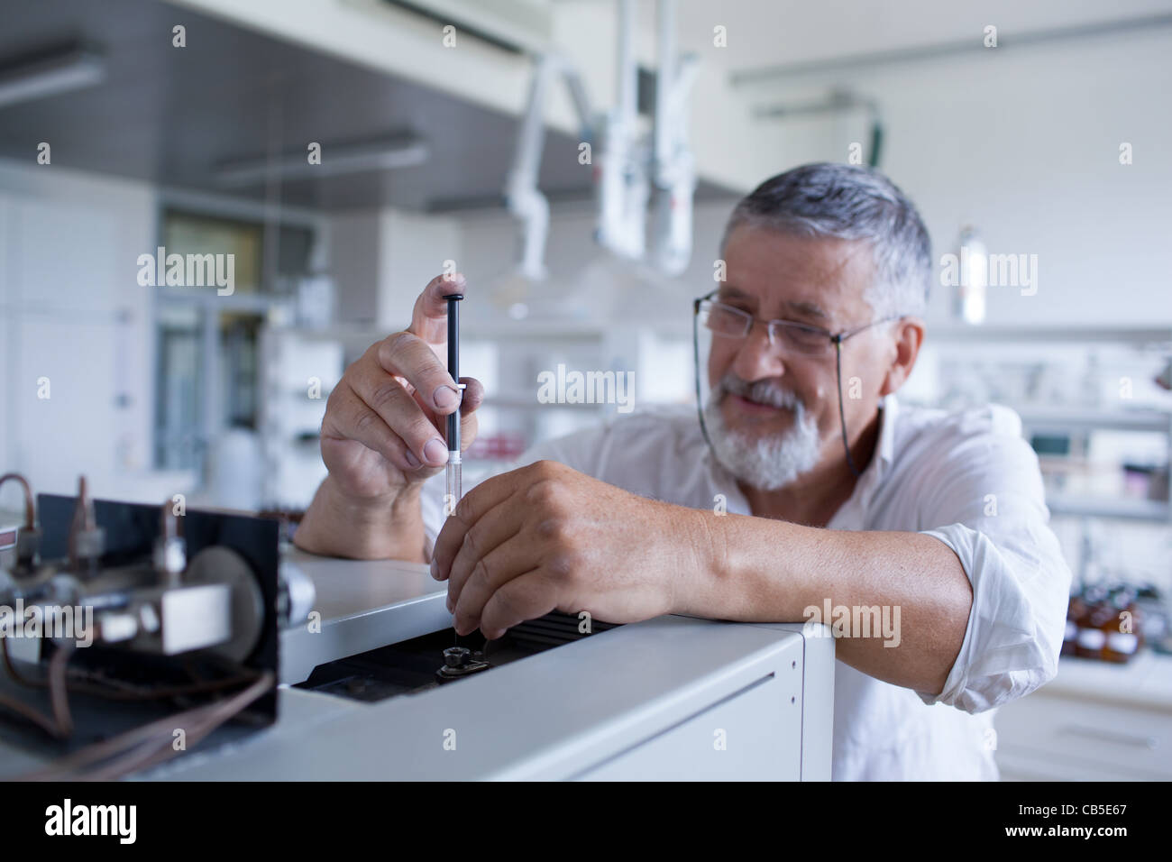 Maschio senior researcher di effettuare attività di ricerca scientifica in un laboratorio usando un cromatografo a gas Foto Stock