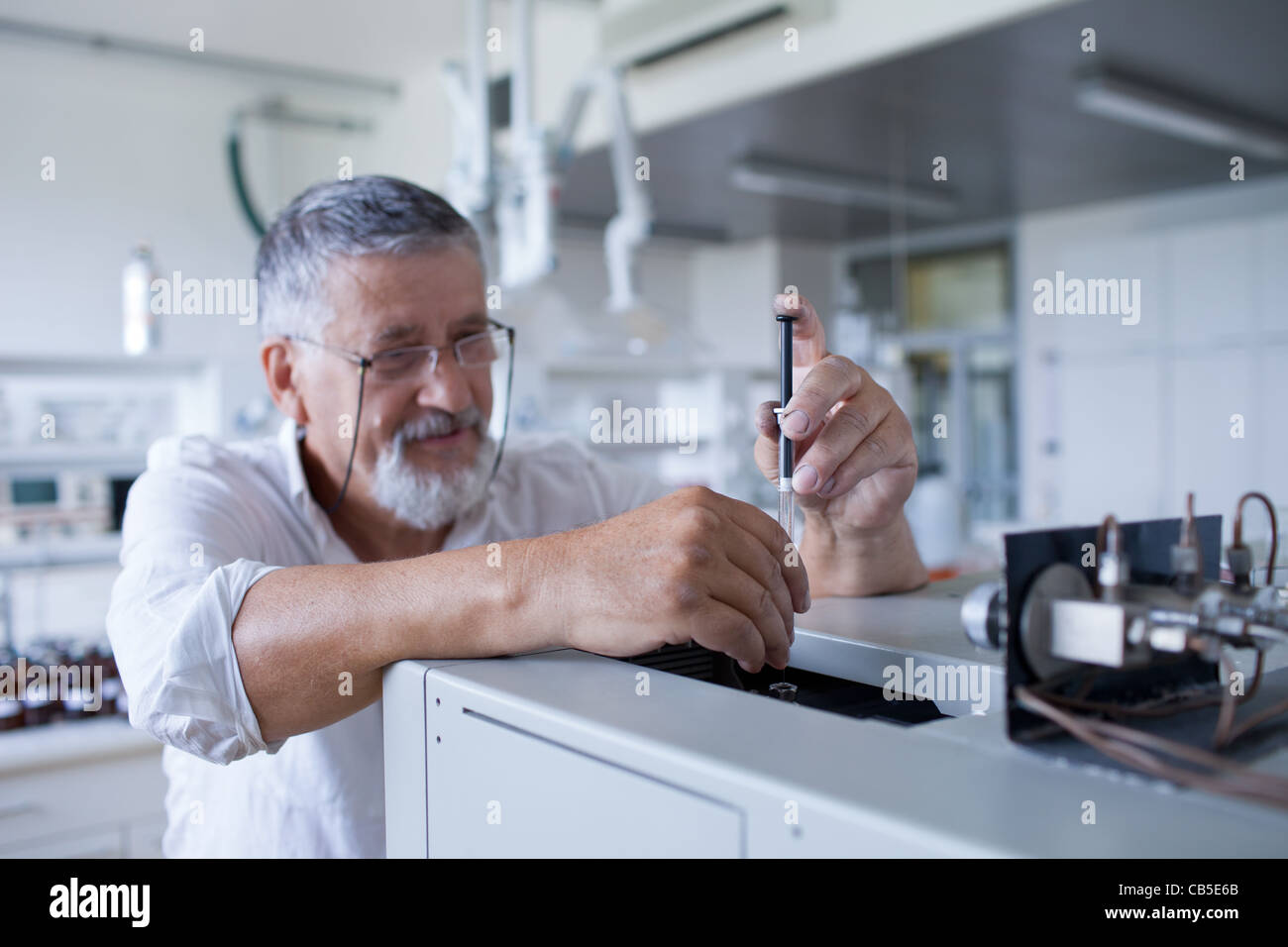 Maschio senior researcher di effettuare attività di ricerca scientifica in un laboratorio usando un cromatografo a gas Foto Stock