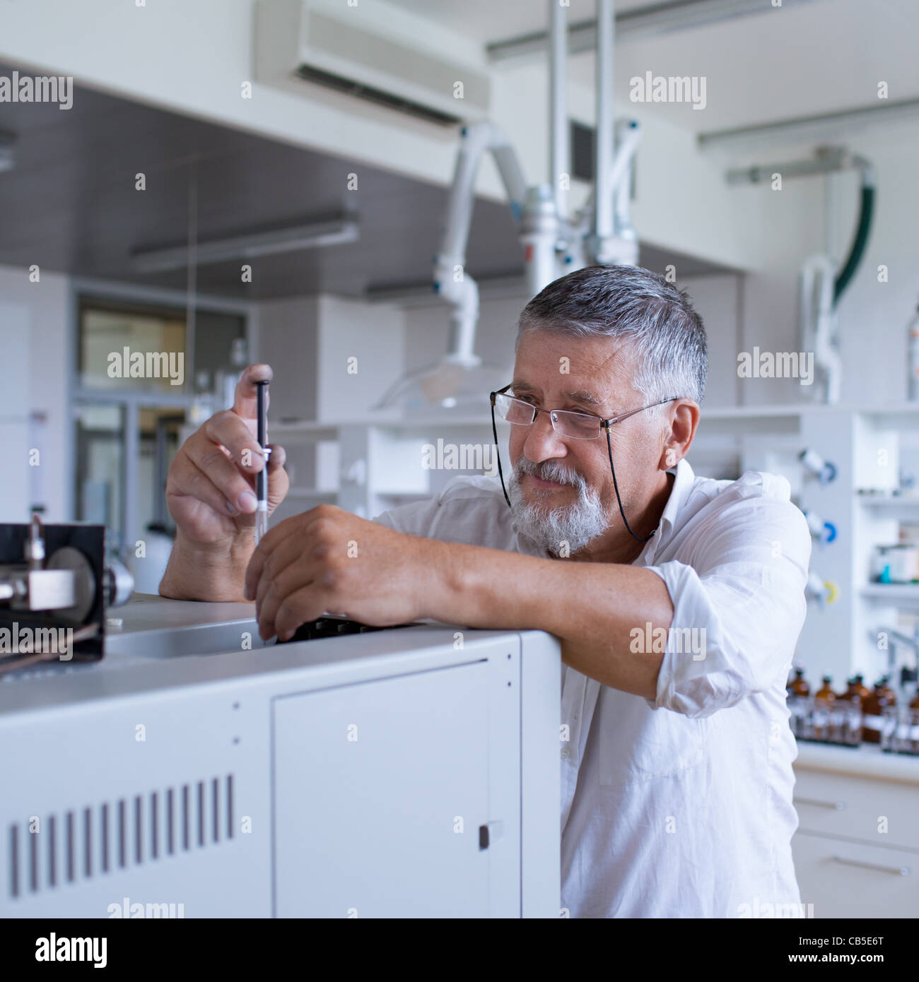 Maschio senior researcher di effettuare attività di ricerca scientifica in un laboratorio usando un cromatografo a gas Foto Stock
