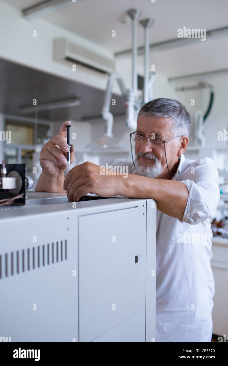 Maschio senior researcher di effettuare attività di ricerca scientifica in un laboratorio usando un cromatografo a gas Foto Stock