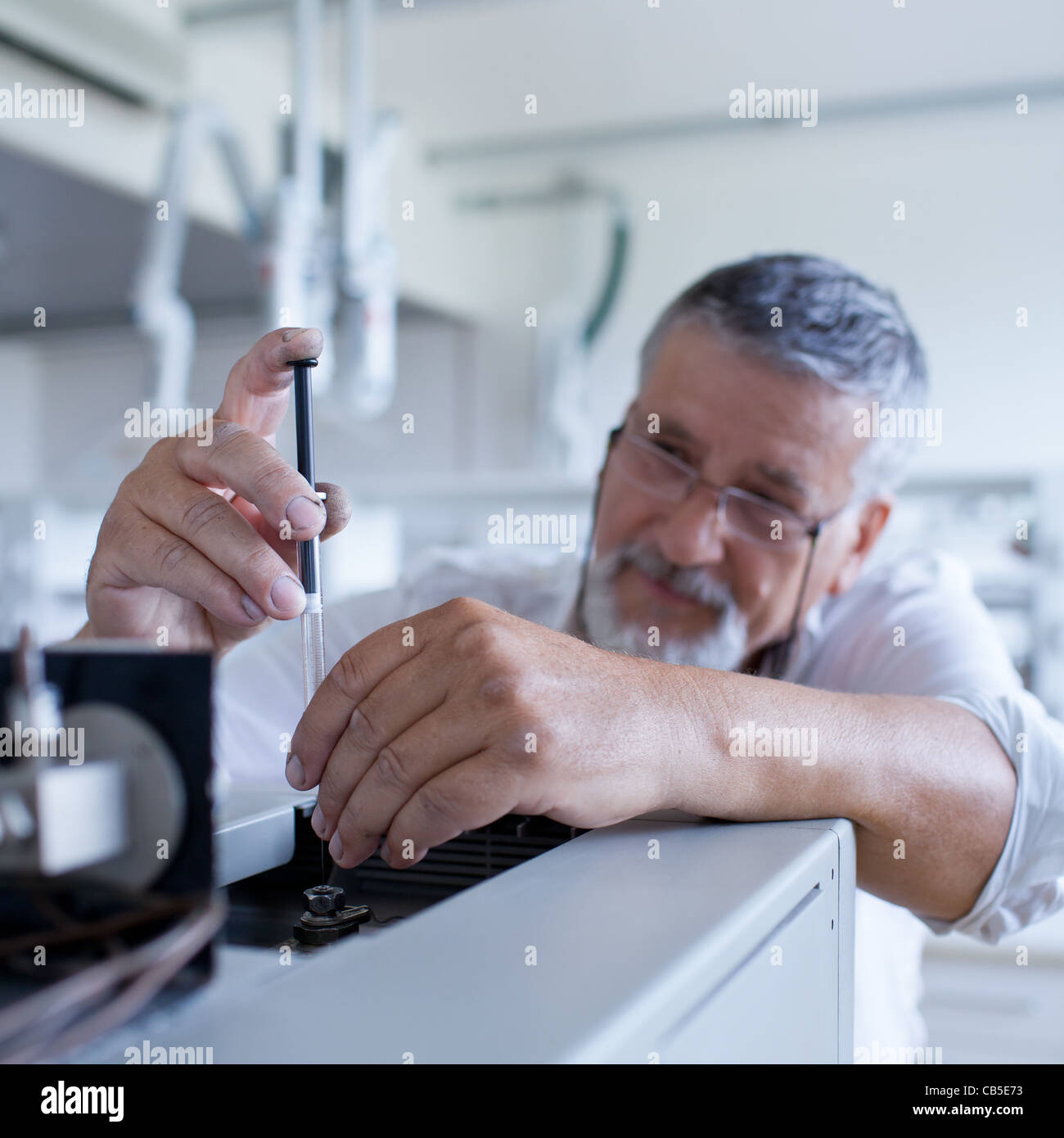 Maschio senior researcher di effettuare attività di ricerca scientifica in un laboratorio usando un cromatografo a gas Foto Stock