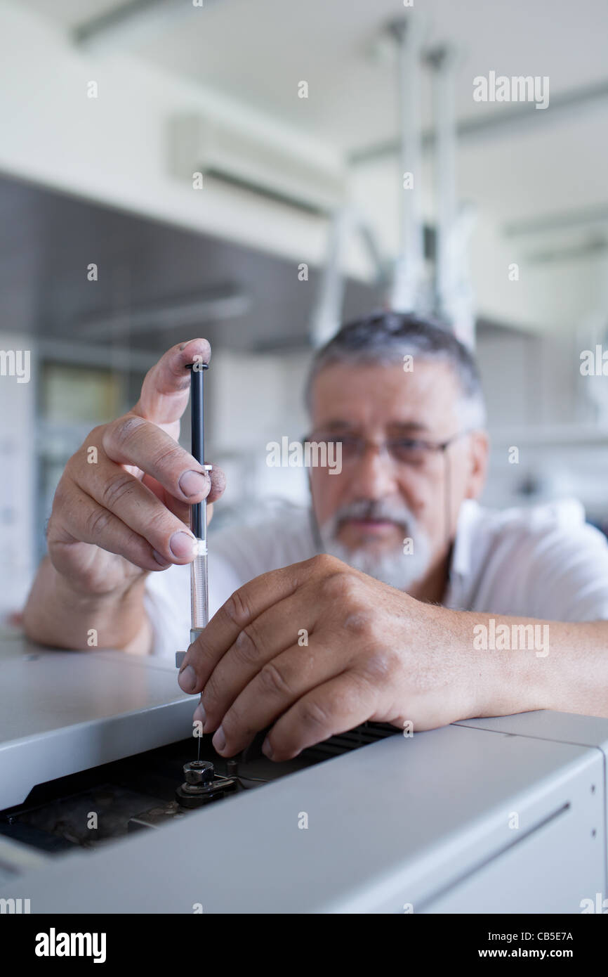 Maschio senior researcher di effettuare attività di ricerca scientifica in un laboratorio usando un cromatografo a gas Foto Stock