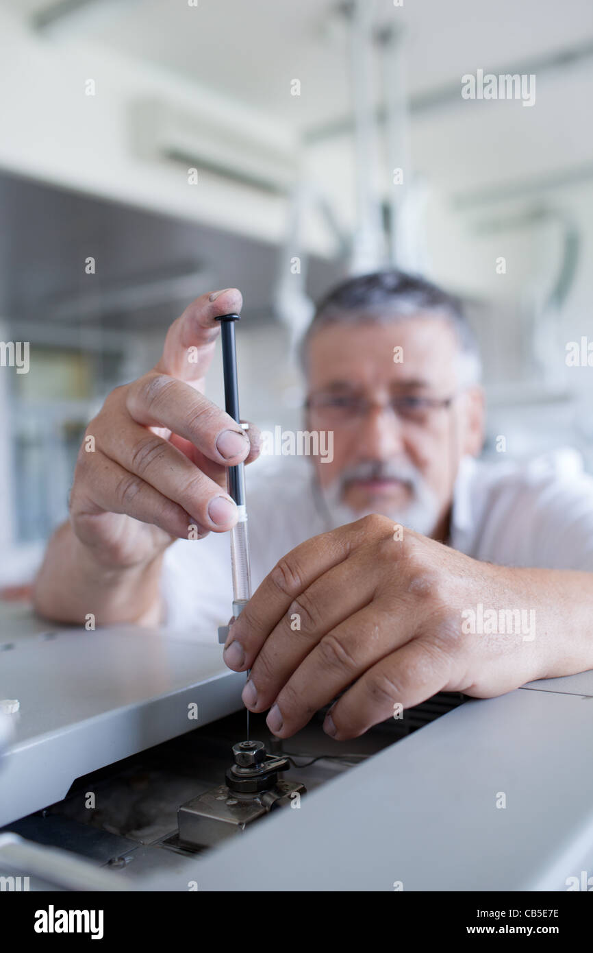 Maschio senior researcher di effettuare attività di ricerca scientifica in un laboratorio usando un cromatografo a gas Foto Stock