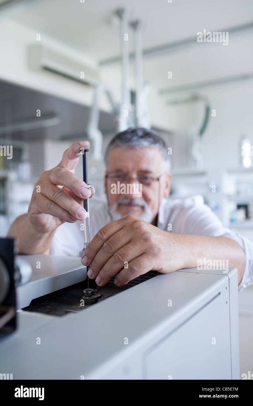 Maschio senior researcher di effettuare attività di ricerca scientifica in un laboratorio usando un cromatografo a gas Foto Stock