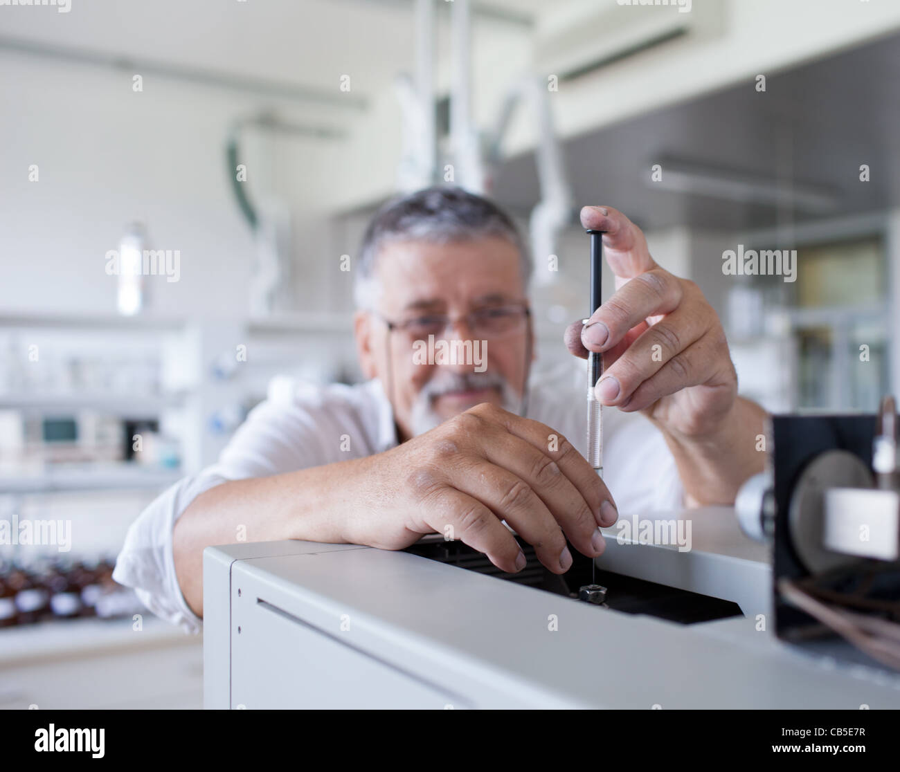 Maschio senior researcher di effettuare attività di ricerca scientifica in un laboratorio usando un cromatografo a gas Foto Stock