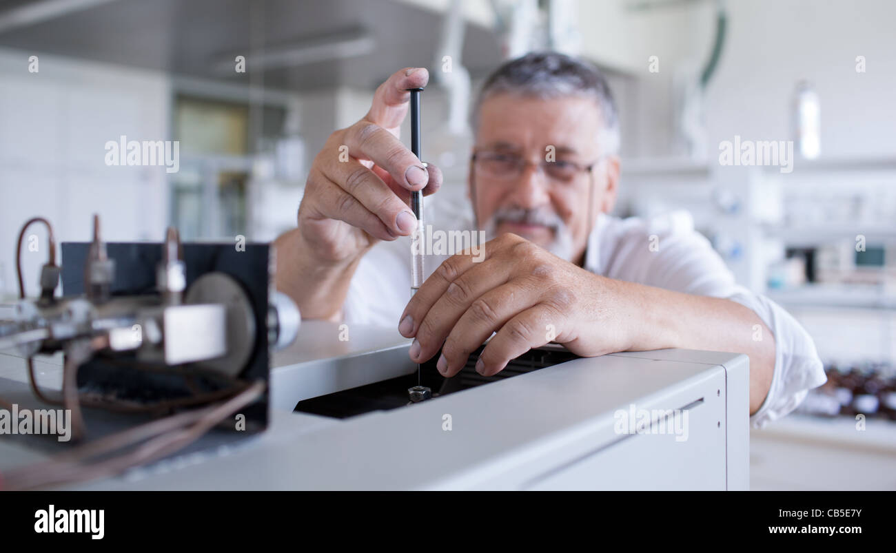 Maschio senior researcher di effettuare attività di ricerca scientifica in un laboratorio usando un cromatografo a gas Foto Stock