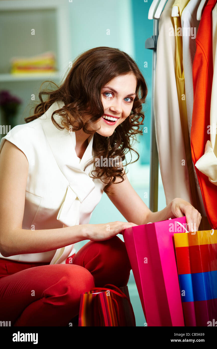 Ritratto di donna graziosa con sacchetti colorati guardando la fotocamera in reparto abbigliamento Foto Stock