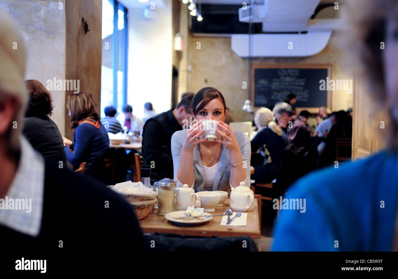 Giovane donna nel suo ventenne 20s seduto da solo in stile francese cafe avente la colazione in Manhattan New York New York STATI UNITI D'AMERICA Photog Foto Stock