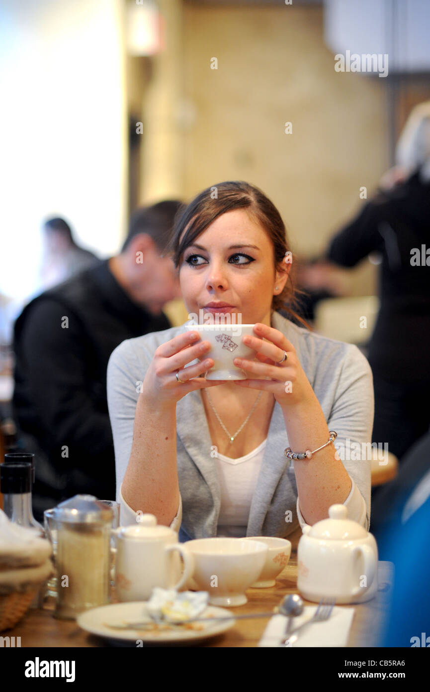 Giovane donna nel suo ventenne 20s seduto da solo in stile francese cafe avente la colazione in Manhattan New York New York STATI UNITI D'AMERICA 2011 Foto Stock