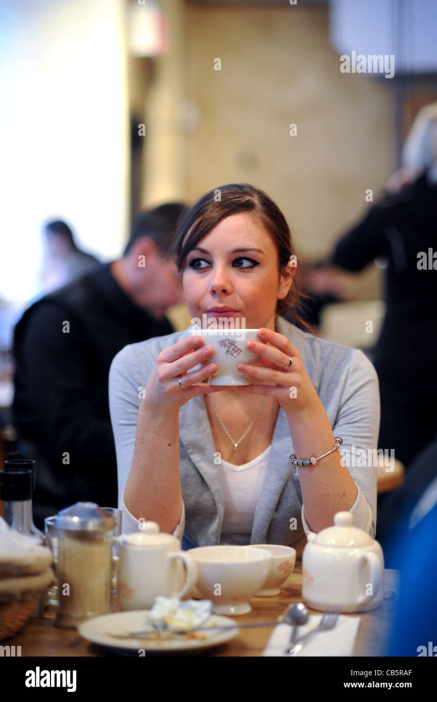 Giovane donna nel suo ventenne 20s seduto da solo in stile francese cafe avente la colazione in Manhattan New York New York STATI UNITI D'AMERICA 2011 Foto Stock