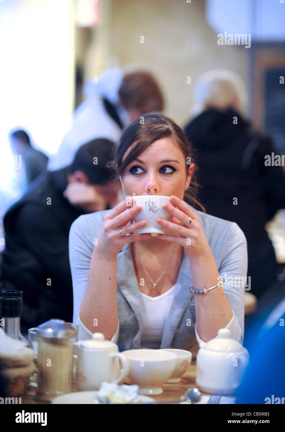 Giovane donna nel suo ventenne 20s seduto da solo in stile francese cafe avente la colazione in Manhattan New York New York STATI UNITI D'AMERICA 2011 Foto Stock