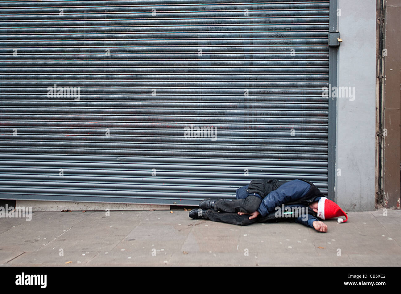 Senzatetto uomo dorme Natale sulla strada Foto Stock