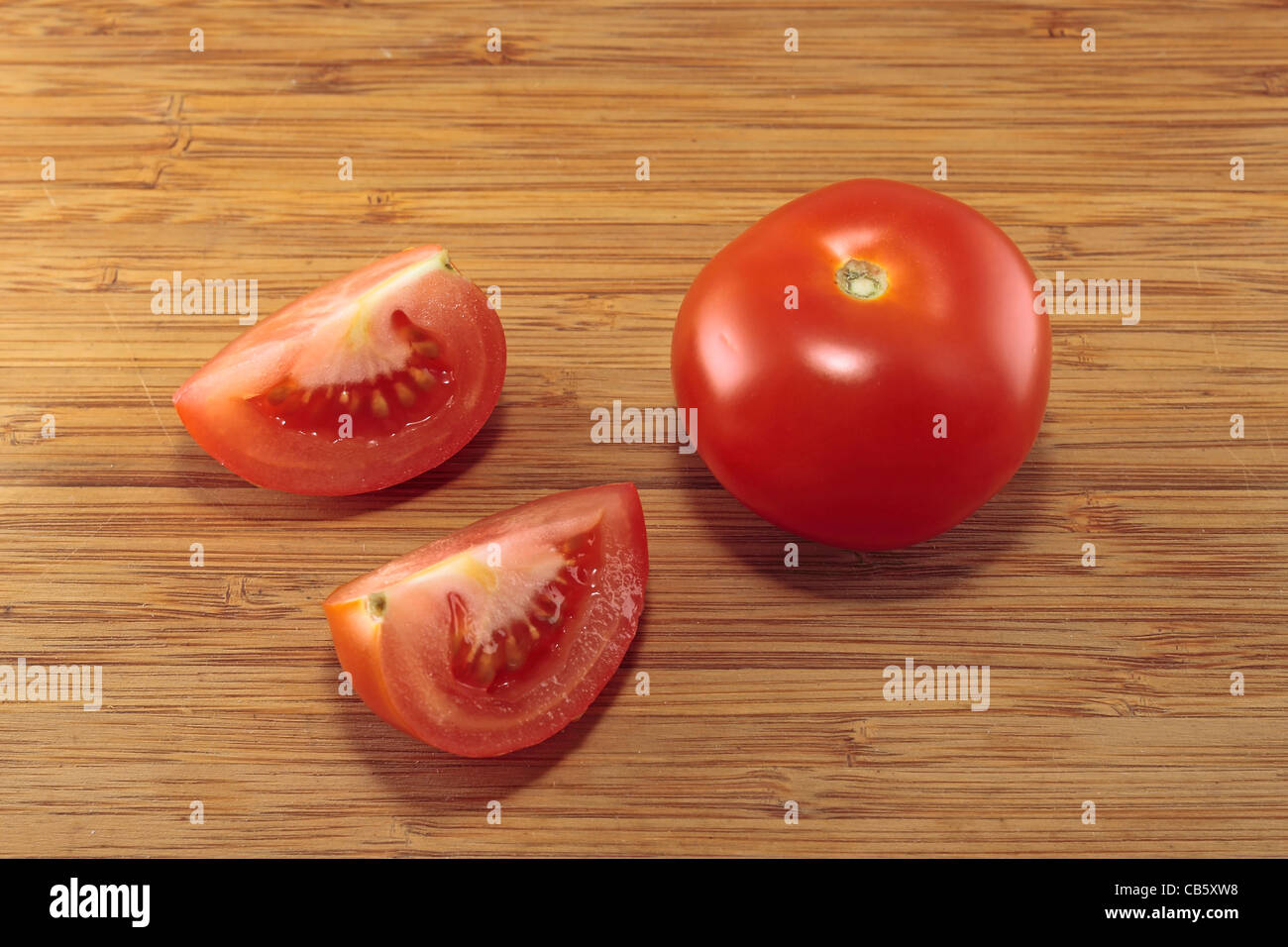 Pomodoro e due quarti di pomodoro su di un tagliere Foto Stock
