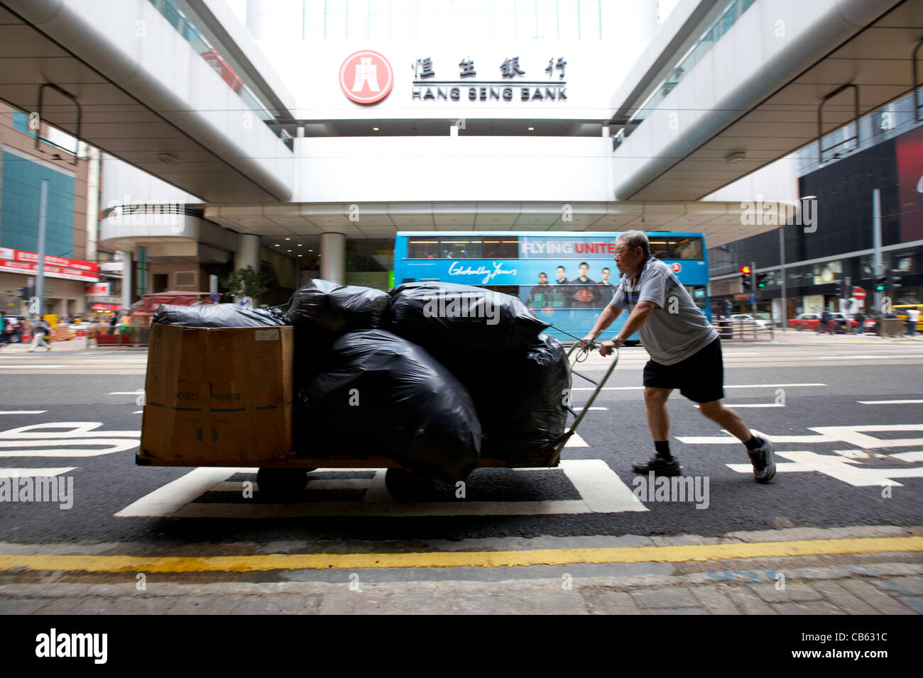 L'uomo spinge il carrello consegna passato Hang Seng bank hq central district, isola di Hong kong, RAS di Hong Kong, Cina deliberata di sfocatura del movimento Foto Stock