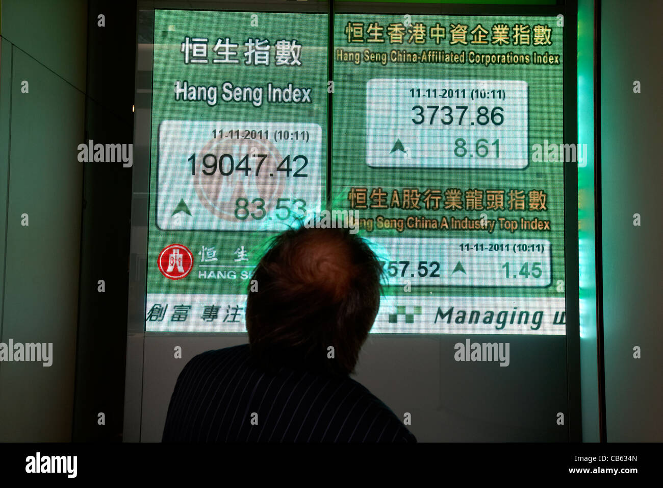 Imprenditore cinese guardando a hong kong indice azionario schermo al Hang Seng bank hq central district, isola di Hong kong, RAS di Hong Kong, Foto Stock