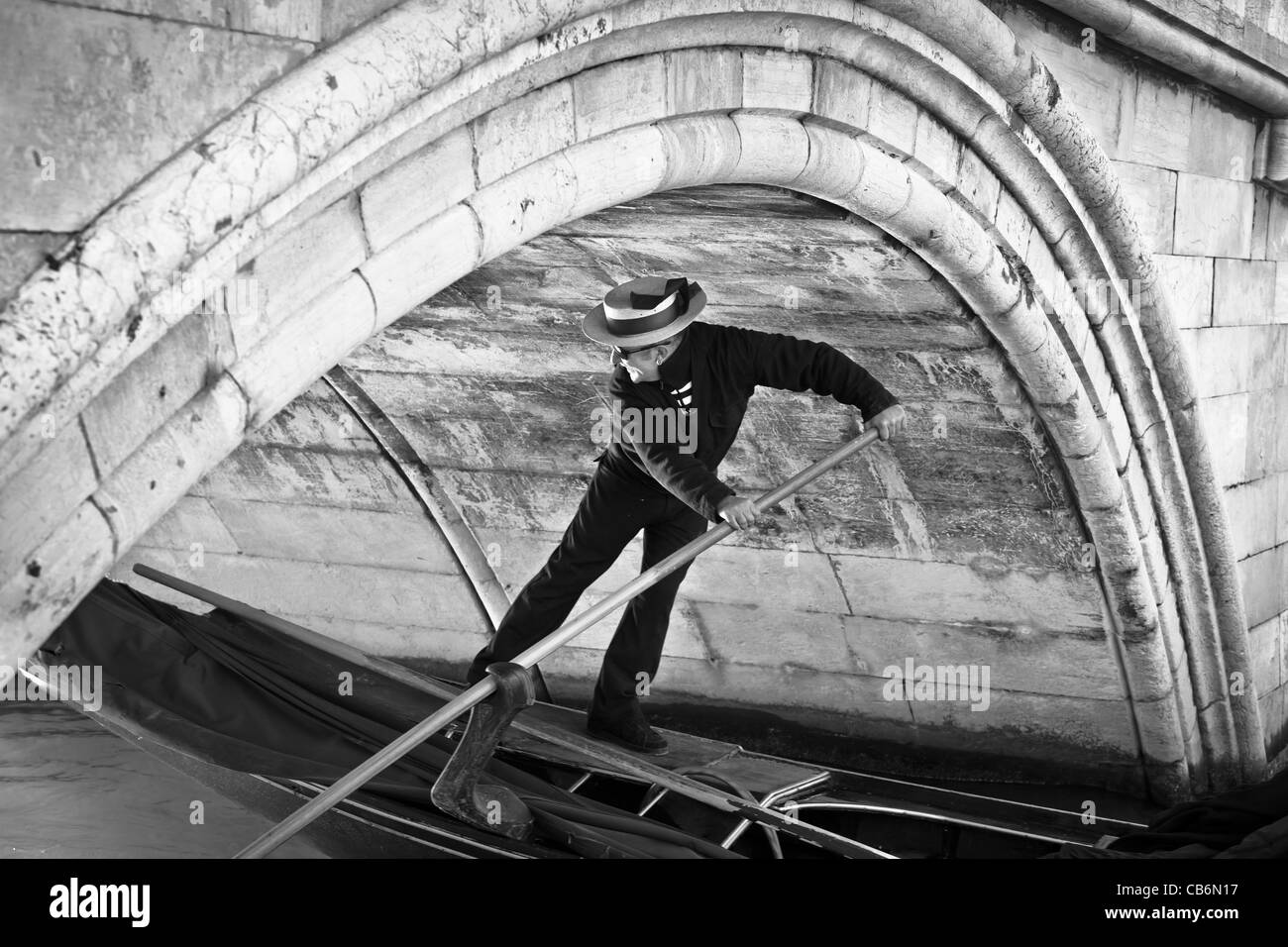 Gondoliere e la sua gondola passando sotto un piccolo ponte in Venezia, Veneto, Italia Foto Stock