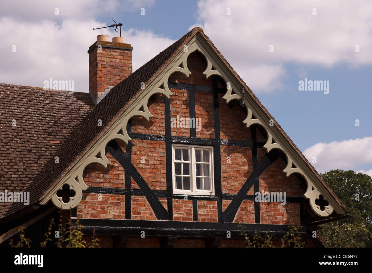 Ornati dipinte di verde eaves sul frontone di mattoni vecchi e trave in legno di quercia casa con travi di legno, poco Dalby, Leicestershire, England, Regno Unito Foto Stock