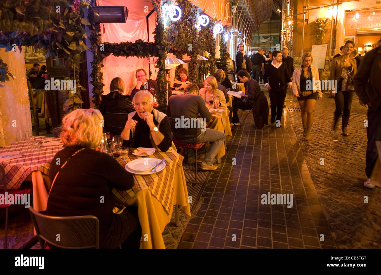 Ristorante tavoli fuori in strada di Trastevere di notte, Roma Italia Foto Stock