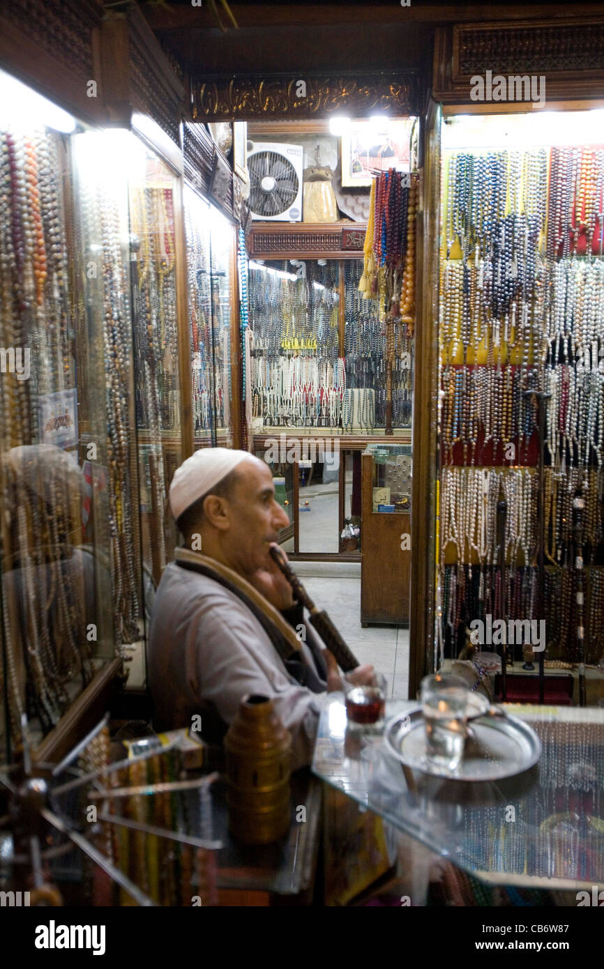 Uomo egiziano di fumare narghile nel suo negozio a Khan el Khalili Cairo Egitto Foto Stock