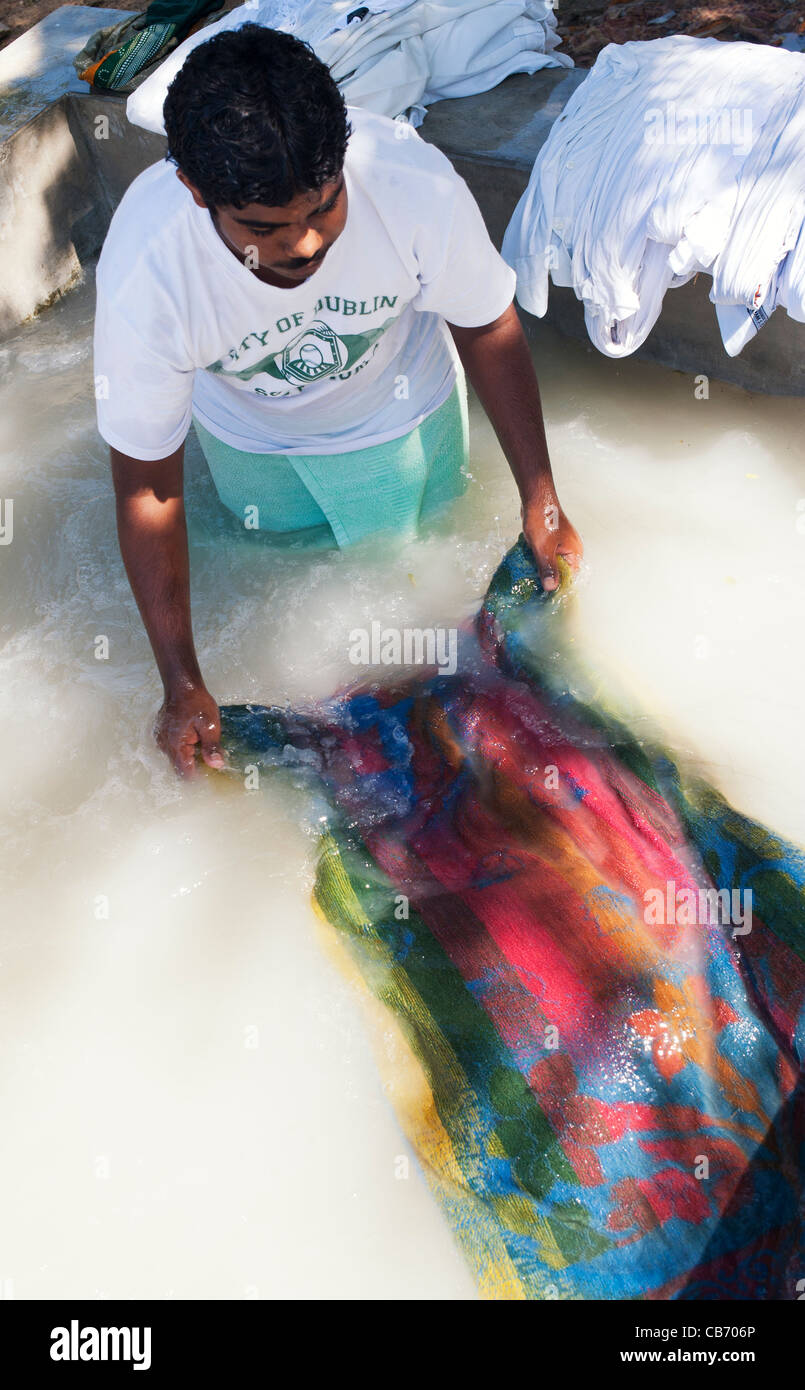 Uomo indiano di lavaggio di un asciugamano colorate a mano in un grande bacino in calcestruzzo. Andhra Pradesh, India Foto Stock