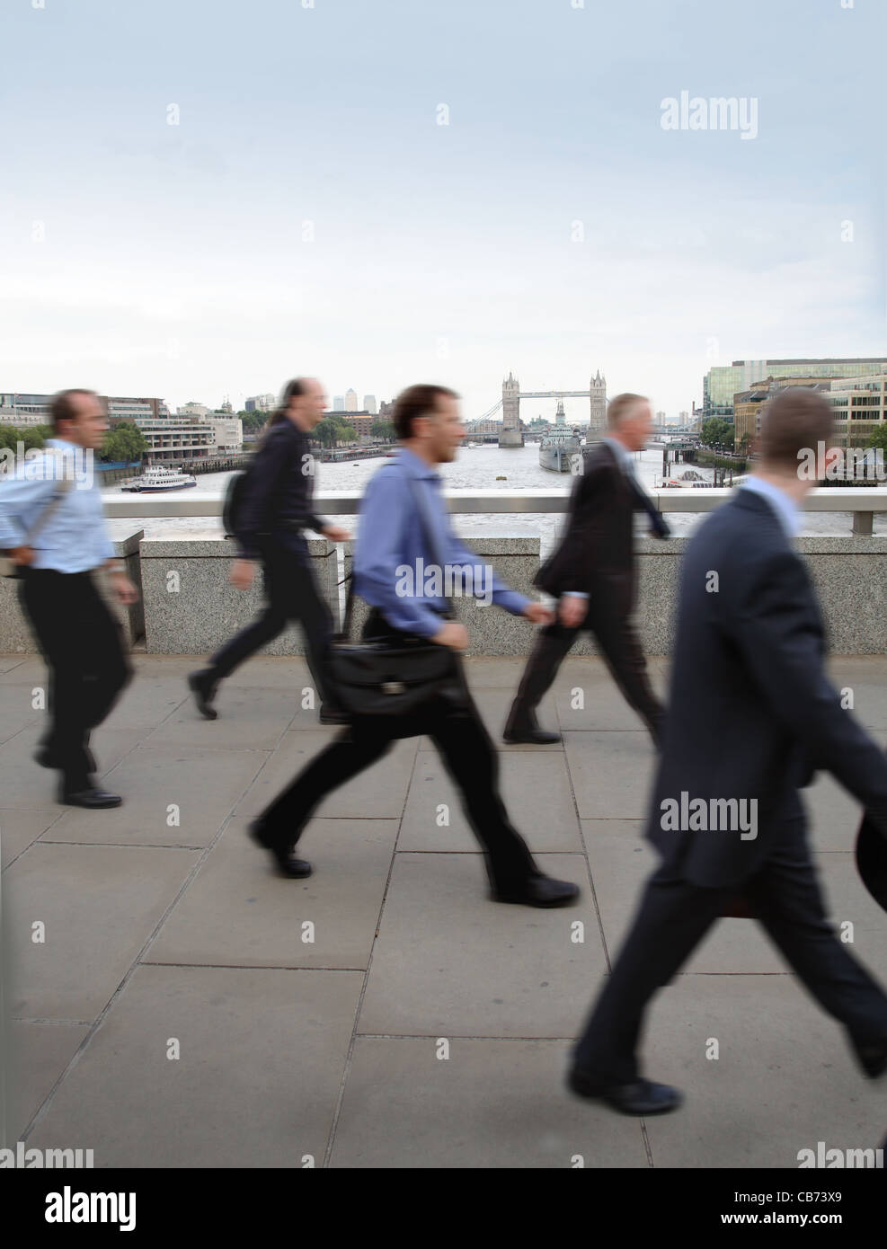I pendolari e i lavoratori della città a piedi sul ponte di Londra. Il fiume Tamigi e il Tower Bridge in background Foto Stock