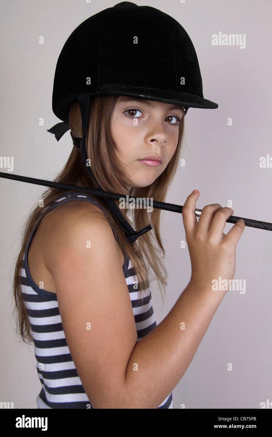 Ragazza giovane indossando cappello di equitazione con frusta Foto Stock