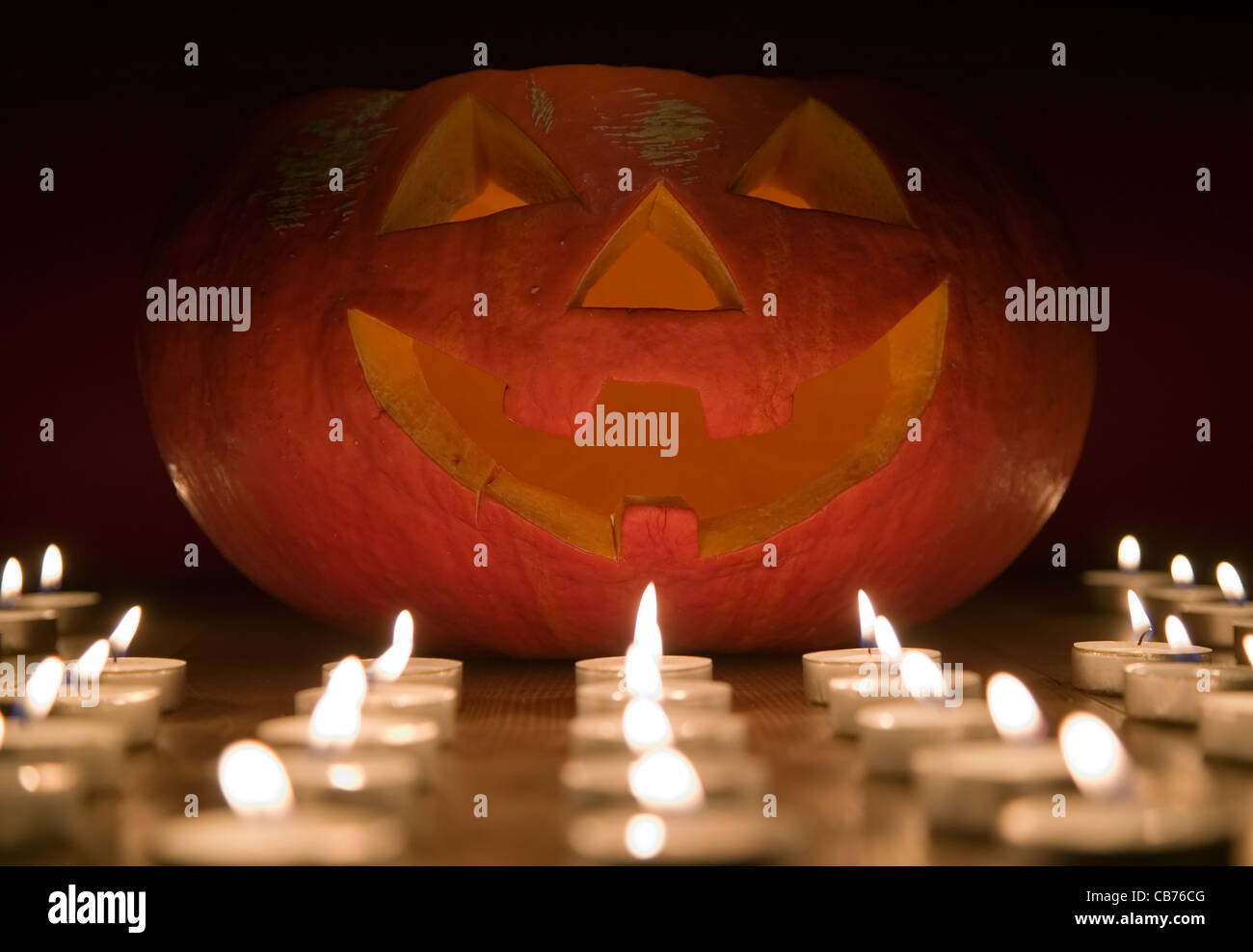 Creepy zucca vicino a candela, concetto di halloween, sfondo rosso Foto Stock