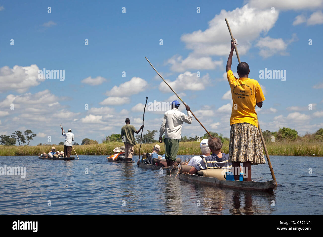 I turisti che viaggiano in tradizionali canoe di legno, mokoro / makoro nell'Okavango Delta, Botswana, Africa Foto Stock
