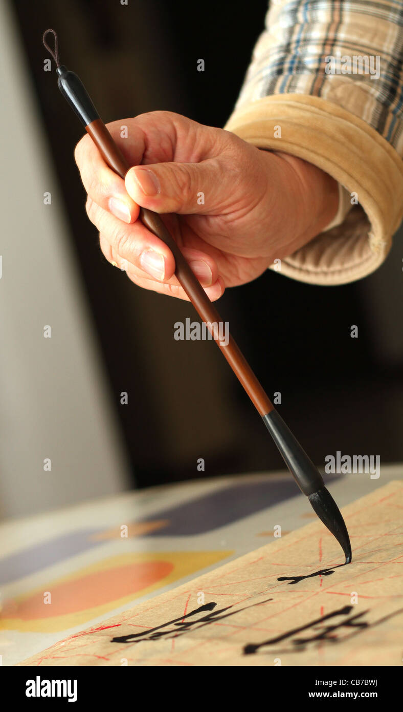 Un vecchio uomo è la pratica di calligrafia utilizzando un pennarello nel suo tempo libero Foto Stock