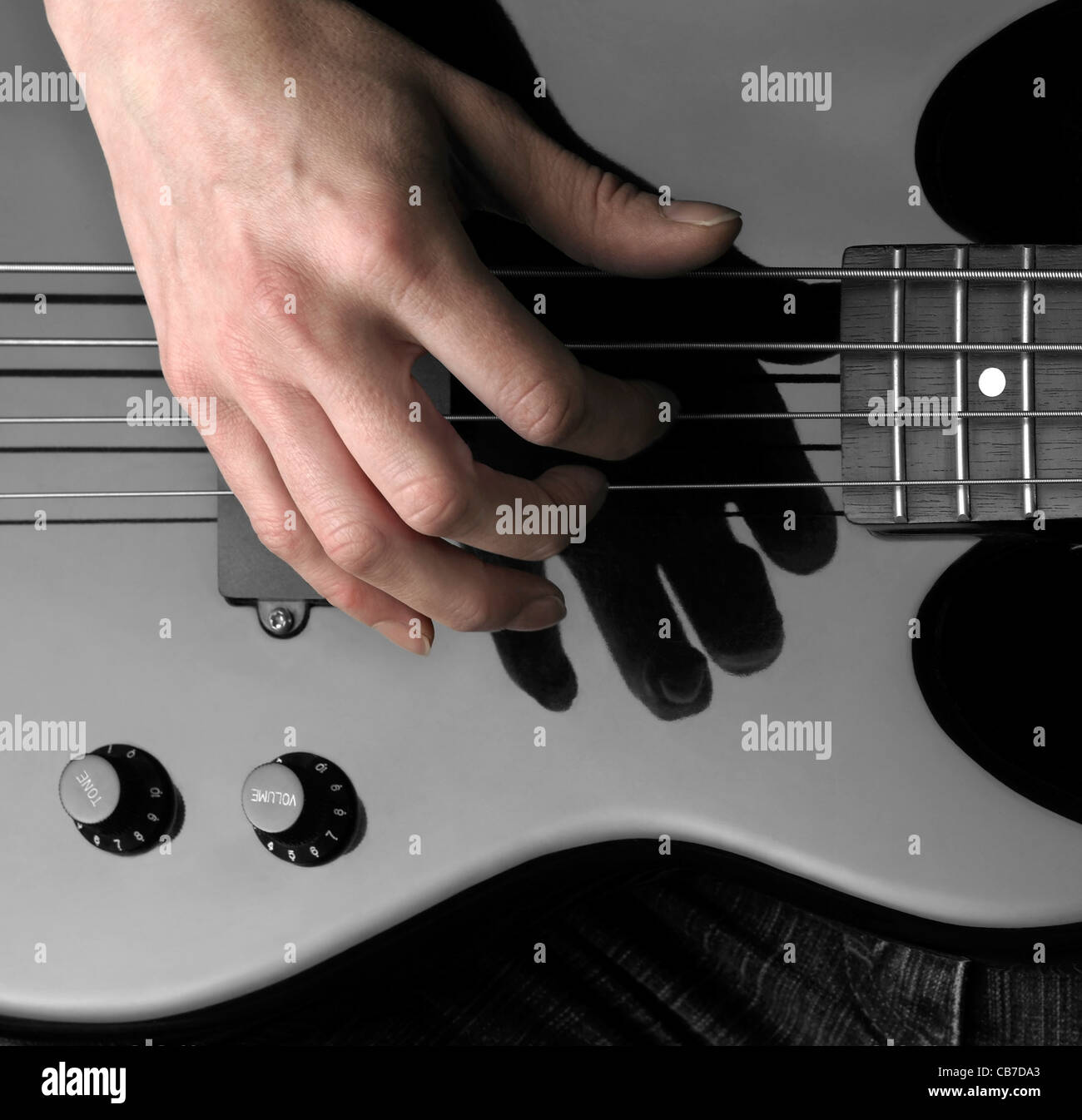 Mano femmina sul dettaglio di un black bass guitar in dark indietro Foto Stock