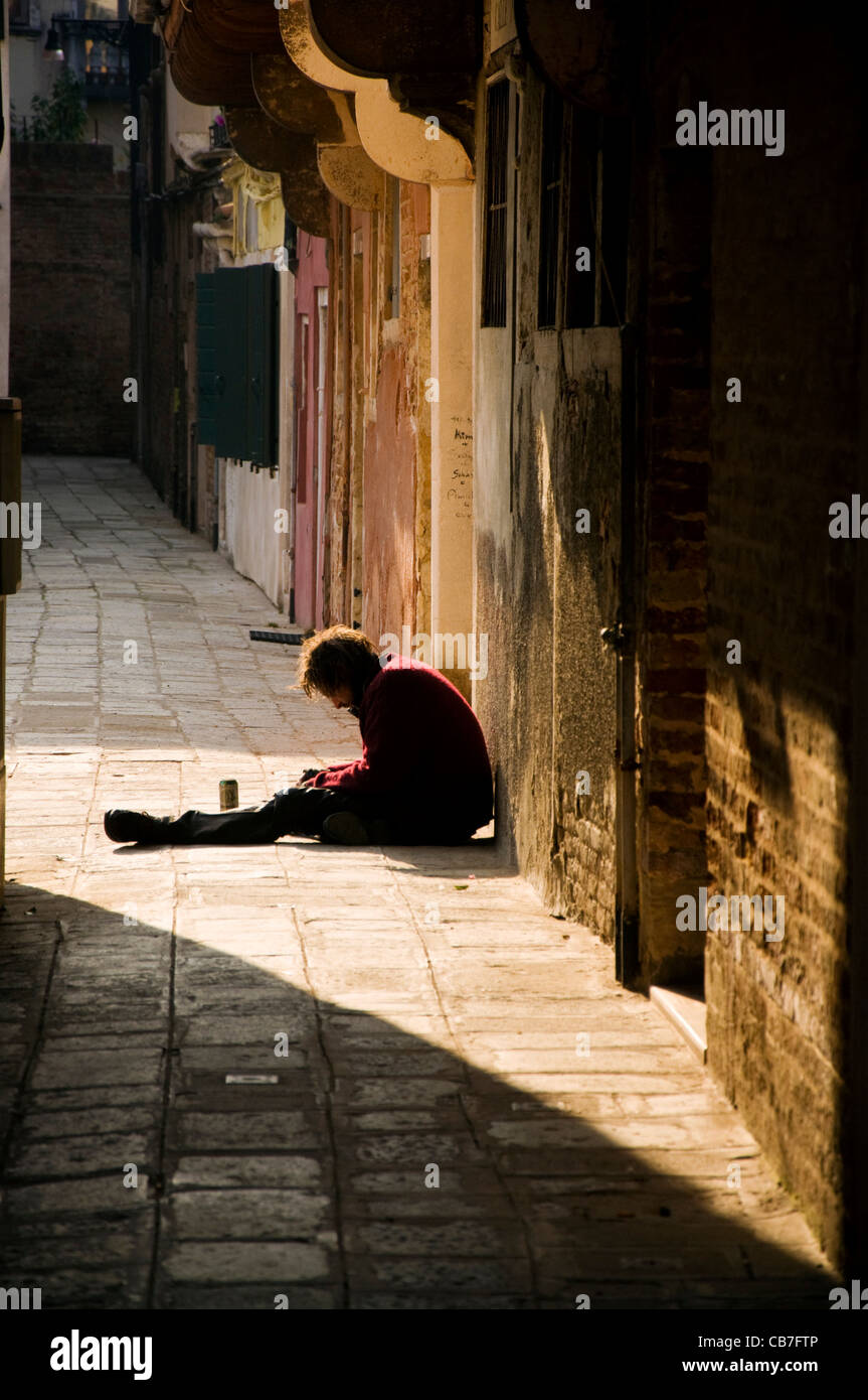 Disoccupati uomo veneziano si siede in strada a mendicare e a bere birra Foto Stock