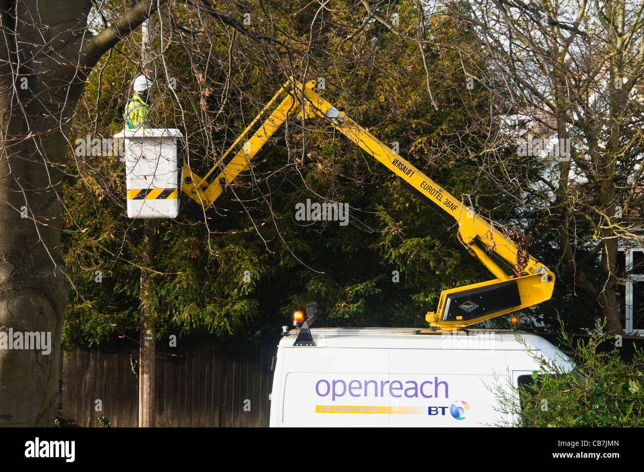 Un BT ( openreach / open reach ) Engineer sollevata fino a un paranco in modo da lui può fissare un cavo da una casa al palo del telegrafo. Regno Unito. Foto Stock