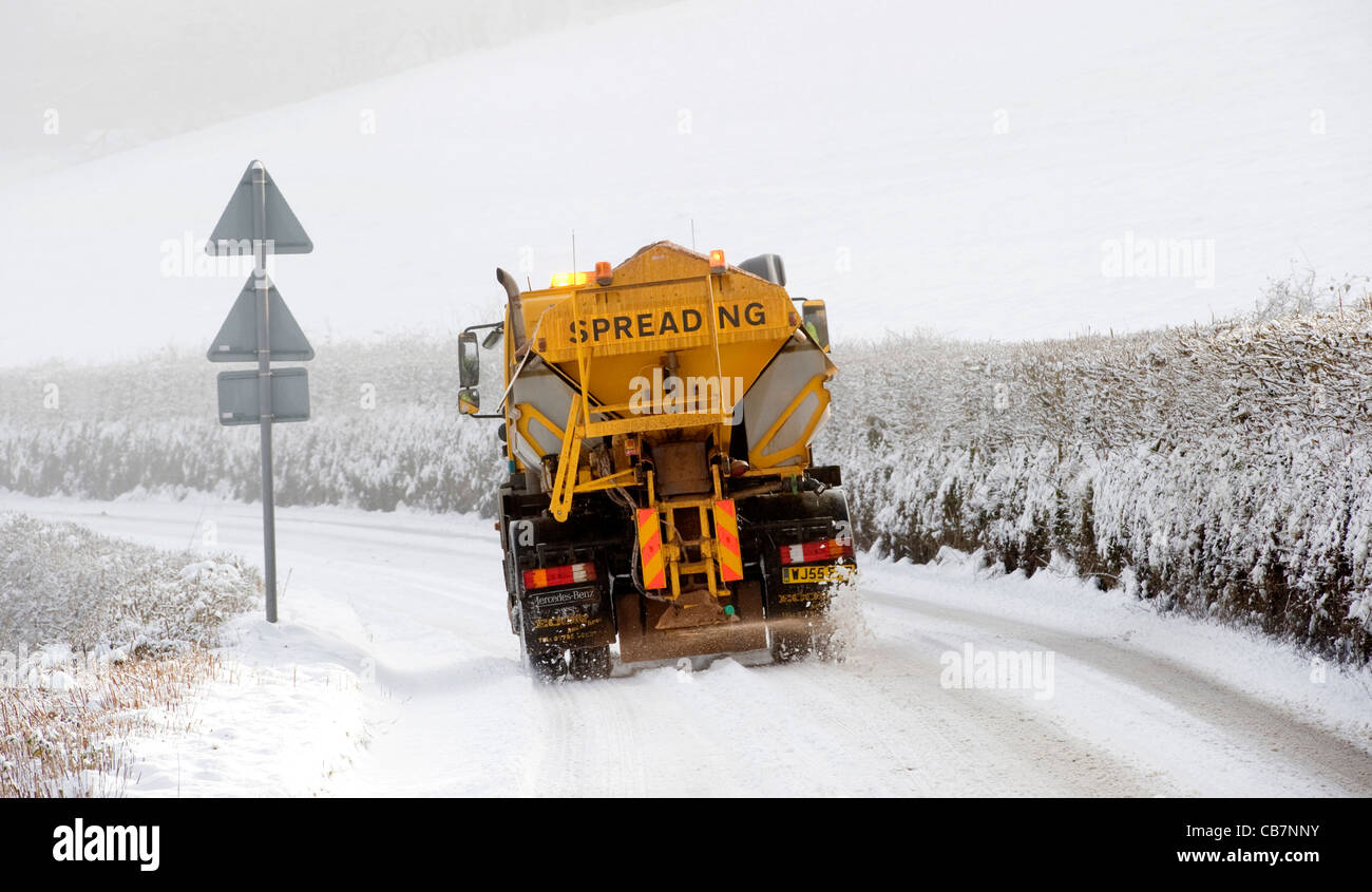 Un giallo Snow Plough grits strade in North Devon come la neve copre il paese Foto Stock