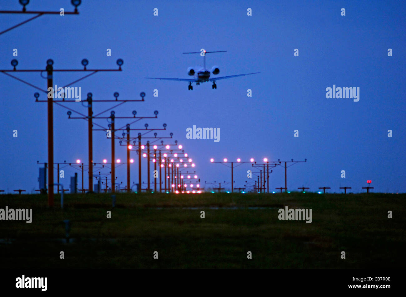 Aereo Jet in avvicinamento al di sopra delle luci pista all'Aeroporto Internazionale Fort Worth di Dallas sotto il cielo nuvoloso ma chiare condizioni atmosferiche Foto Stock