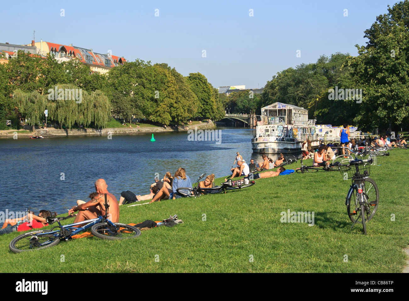 La gente di relax presso il fiume Sprea, banca. Quartiere Kreuzberg di Berlino, Germania. Foto Stock