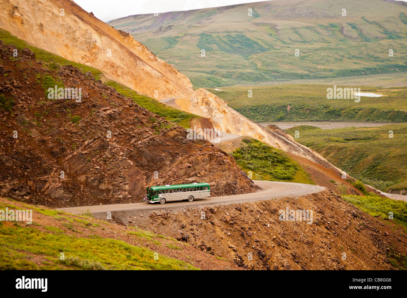 Bus navetta avvolgimento sulla strada sterrata per passare policromo, Parco Nazionale di Denali, Alaska Foto Stock