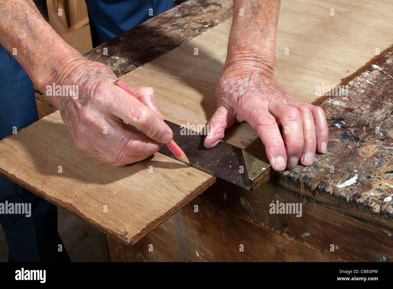 Anziano gentiluomo nella sua officina segnando un pezzo di legno con un set square Foto Stock