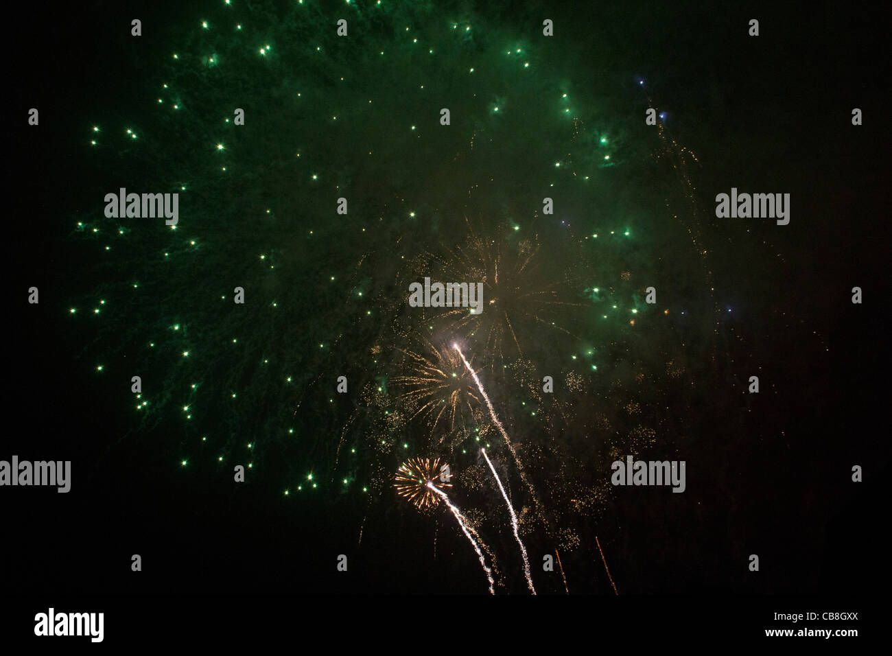 Verde enorme fuochi d' artificio esplosione con tre piccole esplosioni di colore giallo in background. Foto Stock