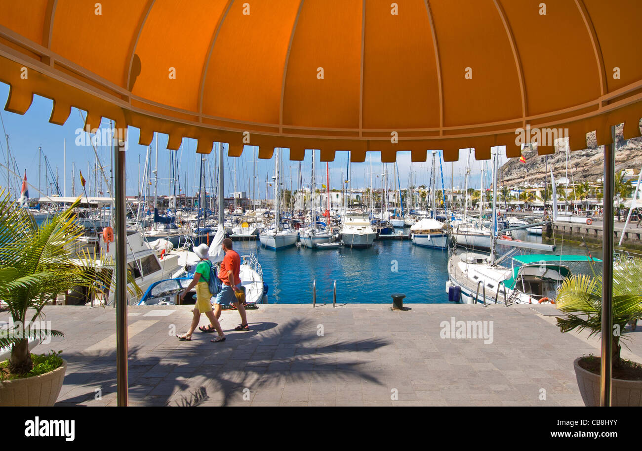 Paio di passeggiare lungo colorato waterside marina lungomare con ristoranti di Puerto de Mogan Gran Canaria Isole Canarie Spagna Foto Stock