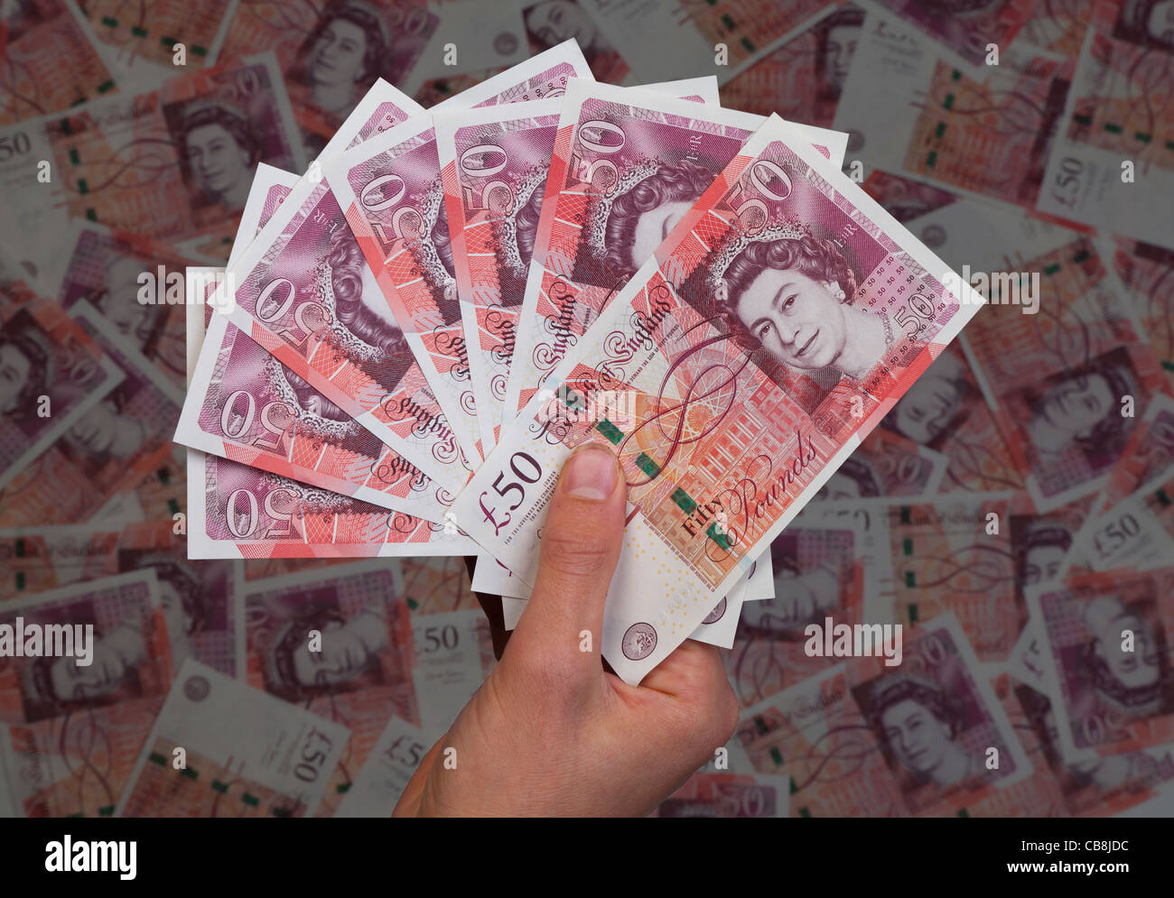 Mano piena di nuovo £50 cinquanta pound note sullo sfondo di 50 banconote Foto Stock