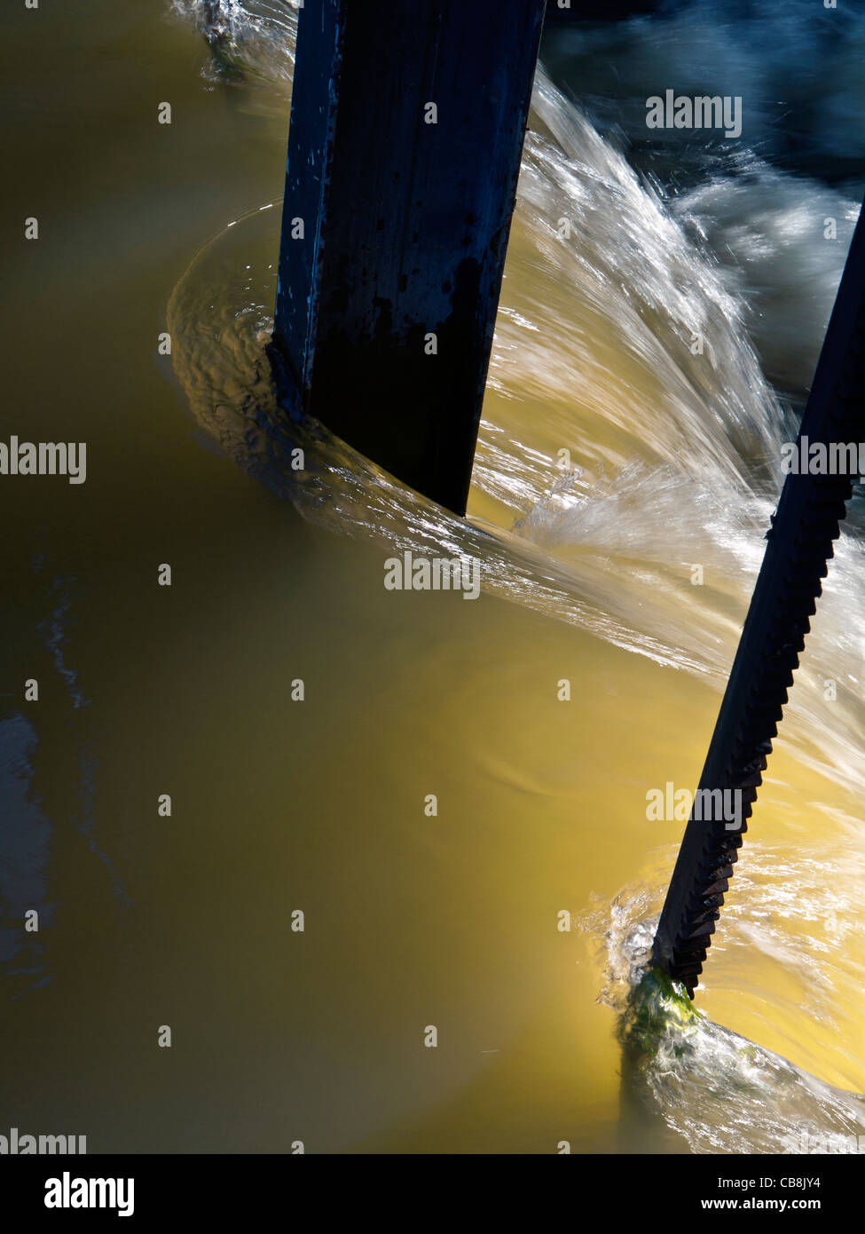 Weir bloccare fiume in piena dopo le recenti piogge intense con acqua soleggiati che scorrono su uno stramazzo Foto Stock